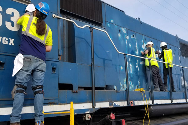 Installers removing railcar graphics for overhaul